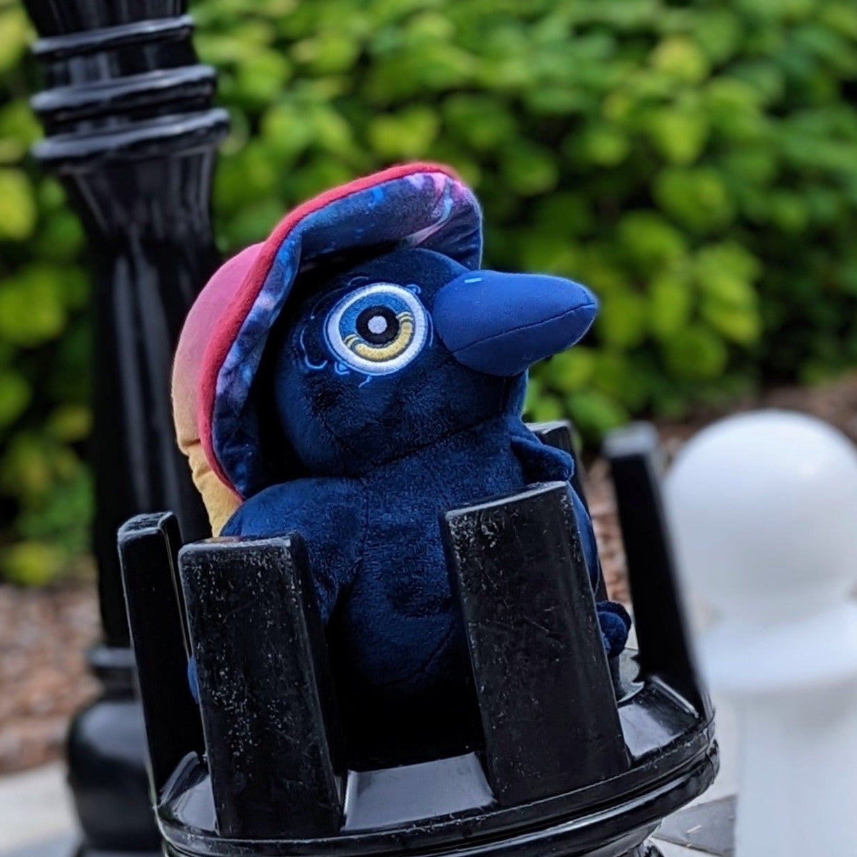 A photograph of Ikarus the Raven Witch Plush on top of a giant chess piece.