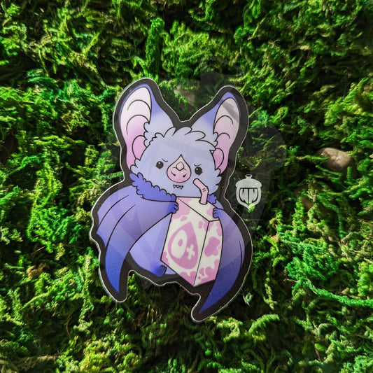Photograph of a mossy background with a vinyl sticker of a purple vampire bat with a pink and white O positive blood juice box.