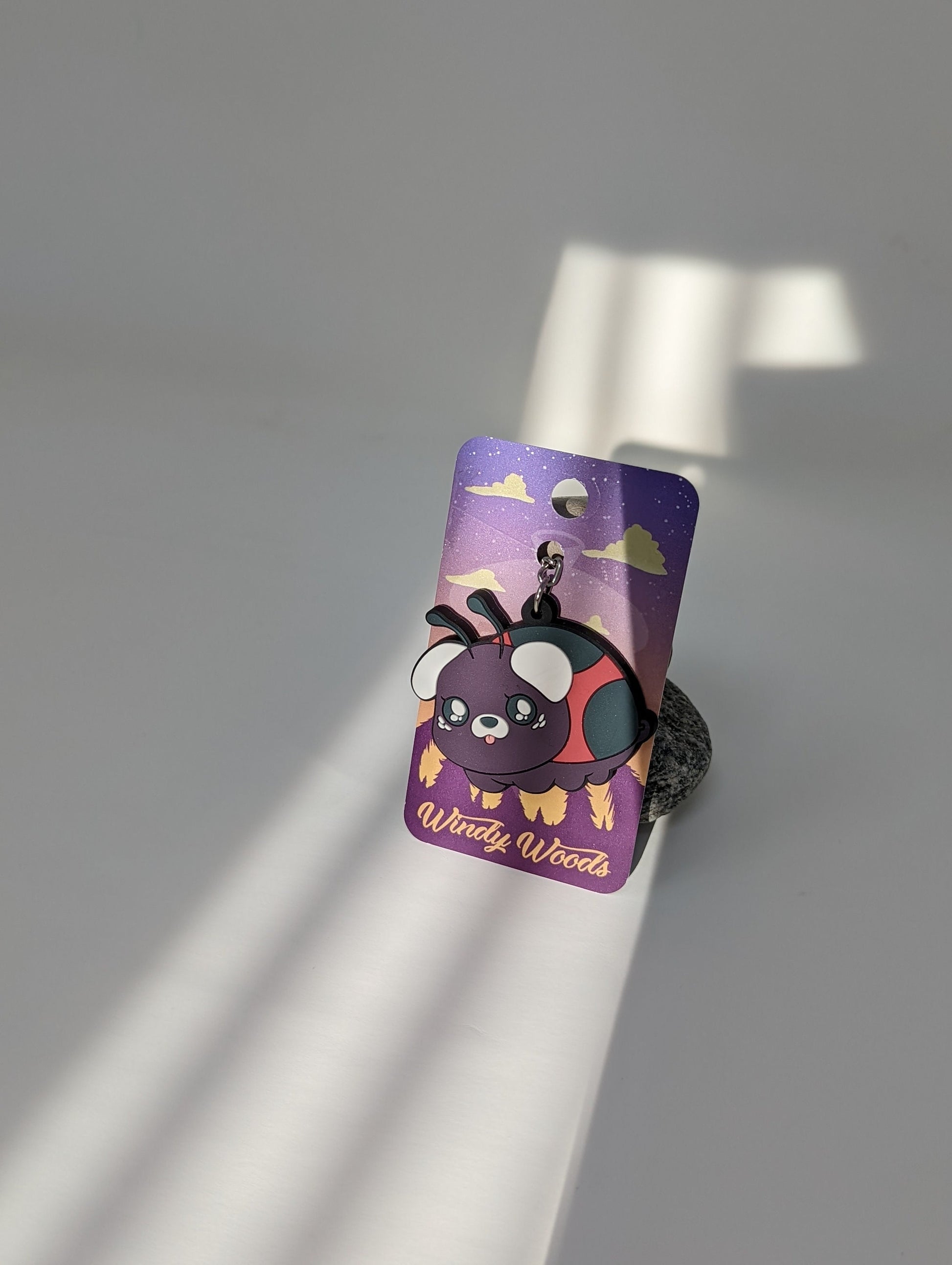 A photograph of a white background with a PVC Keychain of a pug ladybug hybrid creature called a Ladypug.