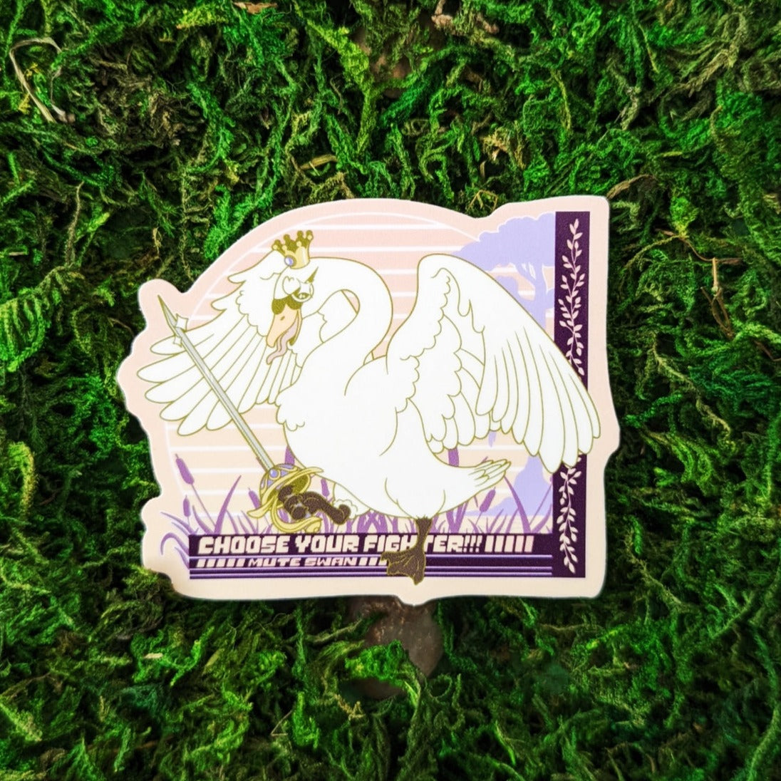 Photograph of a mossy background with a vinyl sticker of a Mute Swan with a crown and a rapier. Under the goose it says, “Choose your Fighter!!! Mute Swan”