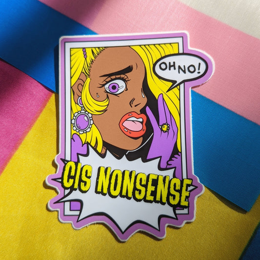 A photograph of a background with the transgender and pansexual pride flags. On top of the flags is a vinyl sticker of a blonde person with purple gloves gasping and saying “OH NO!” under them is an action bubble that says “CIS NONSENSE.”