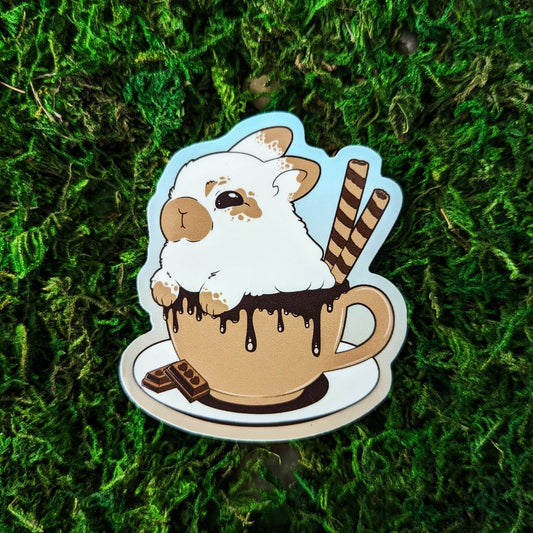 Photograph of a mossy background with a vinyl sticker of a white and tan rabbit in a cup of hot cocoa.