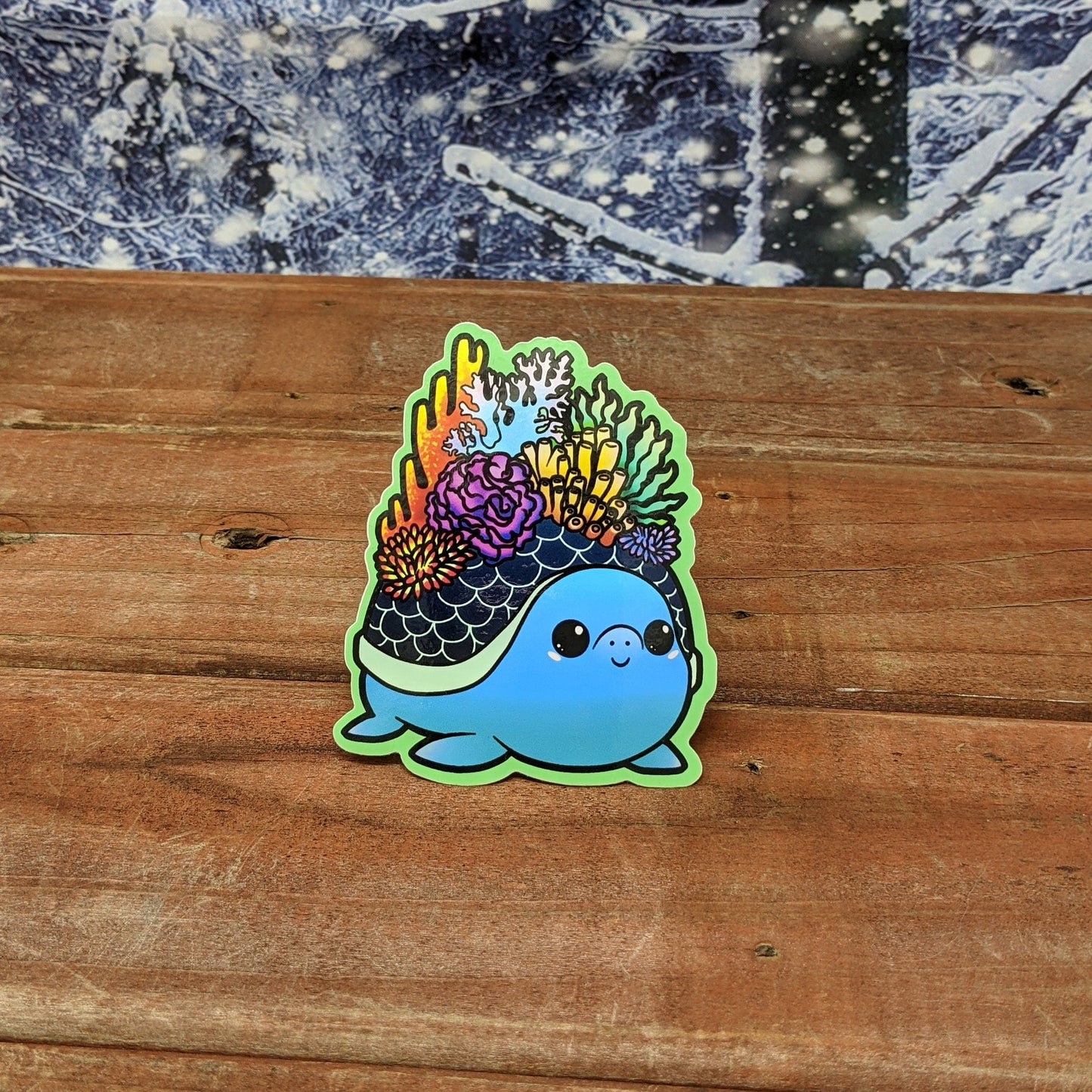 A redwood background with a snowy backdrop. On the wood is a vinyl sticker of a blue turtle with coral growing out of its shell.