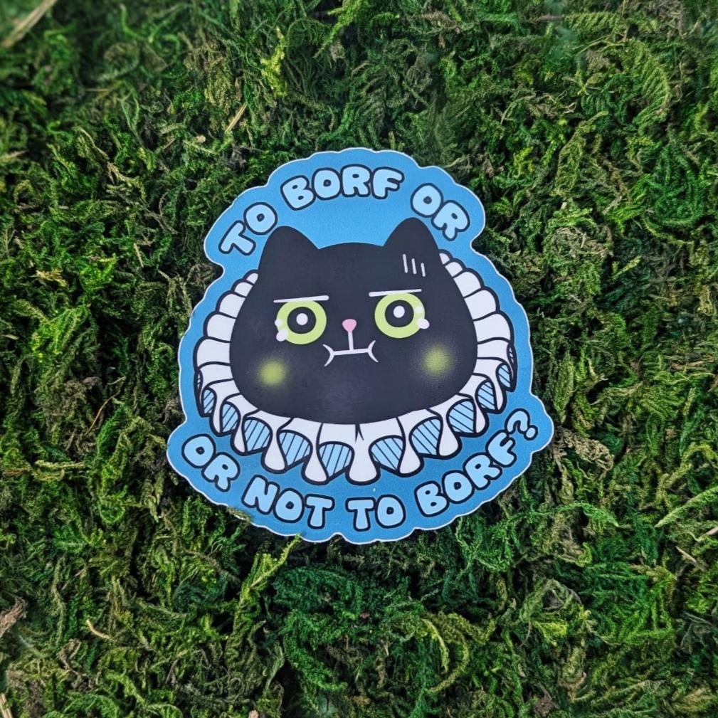 A photograph of a sticker on some moss. The sticker is of a black cat who looks like they're going to vomit with a ruff color on. The sticker says, "To borf or not to borf?"