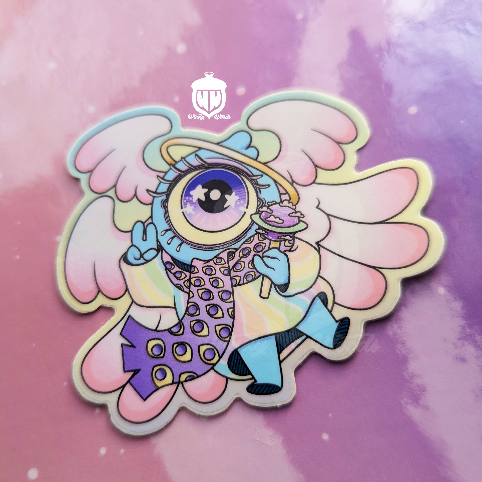 A photograph of a vinyl sticker against a pink and purple background. The sticker features Chamuel, the adorable biblically accurate angel. The sticker is approx 2.5 by 3 inches and is made of super durable waterproof vinyl.