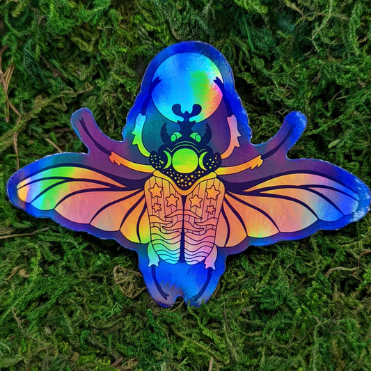 Photograph of a mossy background with a holographic vinyl sticker a beetle with a moon theme.