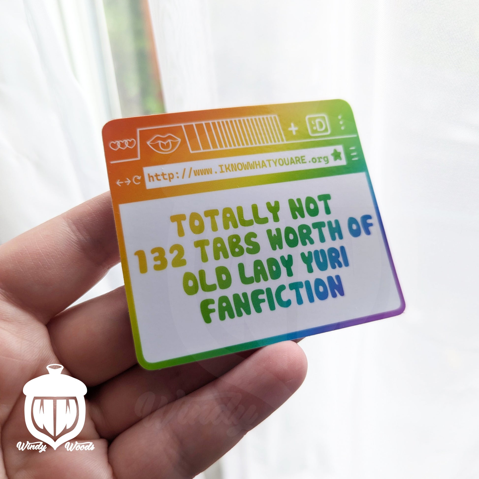 A photograph of a vinyl sticker being held in an outstretched hand. The sticker shows an internet browser in rainbow colors. The page says, "Totally Not 132 tabs worth of old lady yuri fanfiction" and the website above it says, "WWW.Iknowwhatyouare.org"