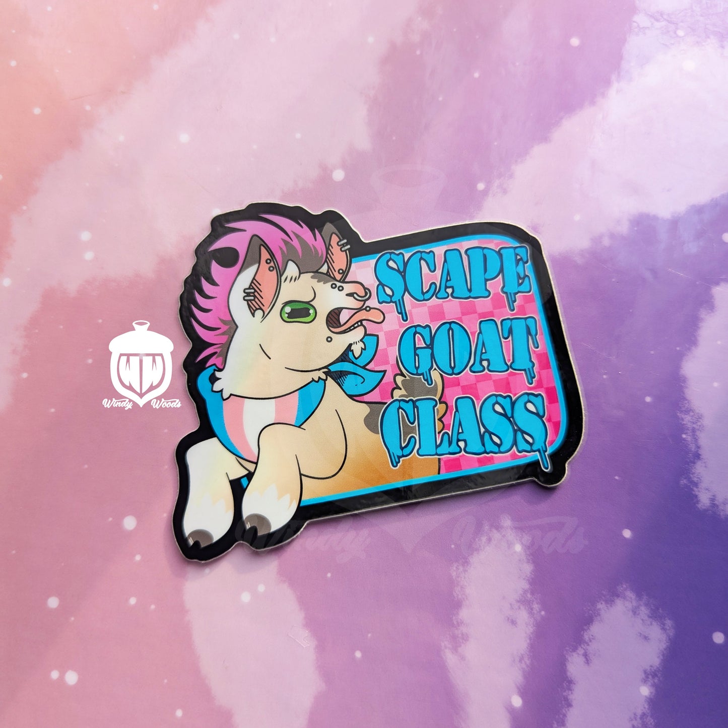 A photograph of a vinyl sticker against a pink and purple background. The sticker features a cute goat with piercings and a pink mohawk. The goat is wearing a bandana with the transgender flag on it. Next to the goat it says, “Scapegoat Class.”