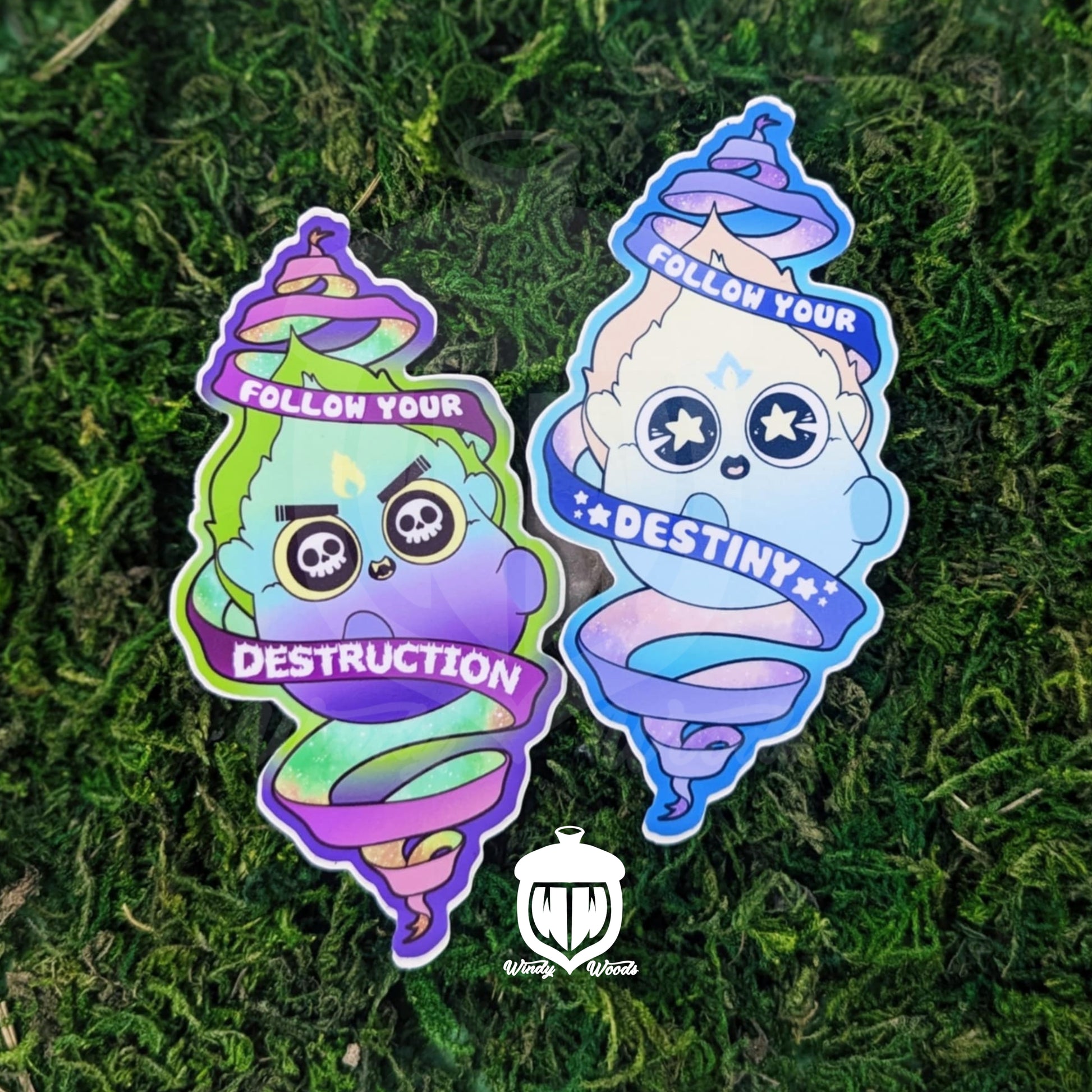 A photograph of two sticker on some moss. The sticker features two Will-o'-the-wisp. One has skulls in it's eyes and the flames are green blue and purple. A scroll around him says, "Follow your destruction." The other has stars in its eyes and is light yellow, blue, and orange. A scroll around him says, "Follow your Destiny."