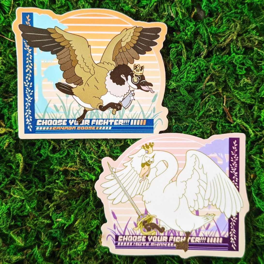 Photograph of a mossy background with a vinyl sticker of a Canada Goose with a cardboard crown and a kitchen knife. Under the goose it says, “Choose your Fighter!!! Canada Goose” 