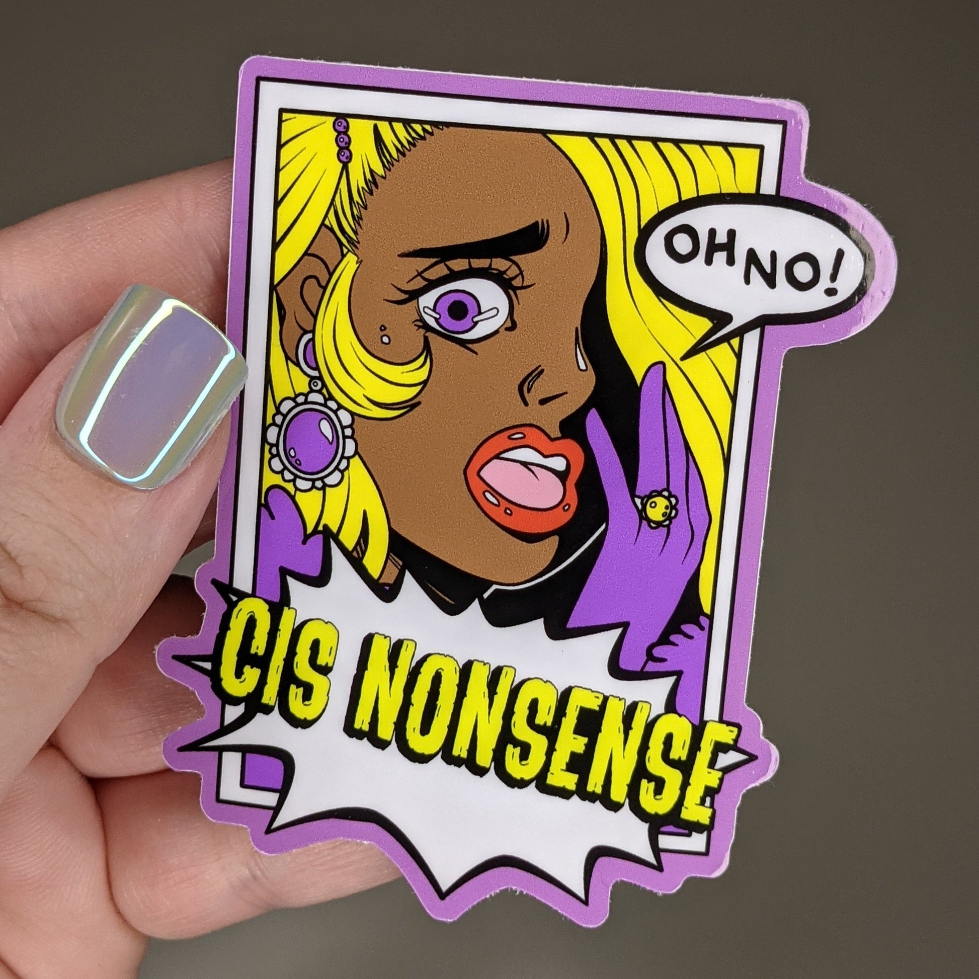 Photograph of a person holding a vinyl sticker of a blonde person with purple gloves gasping and saying “OH NO!” under them is an action bubble that says “CIS NONSENSE.”