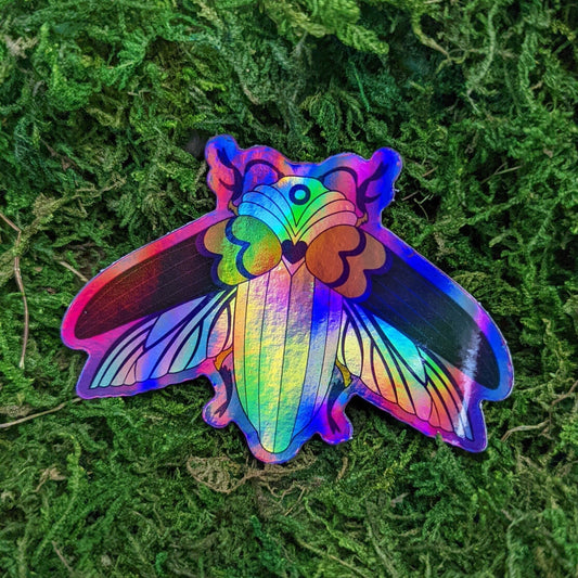 Photograph of a mossy background with a holographic vinyl sticker a beetle with progress flag theme.