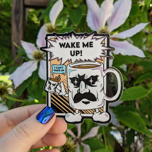 A photograph of a vinyl sticker being held in front of a clematis plant. The vinyl sticker is a comic style coffee cup with a mustache holding a smaller coffee cup. The bigger cup is saying, “Wake me up!” The smaller cup is saying, “Can’t wake up!”